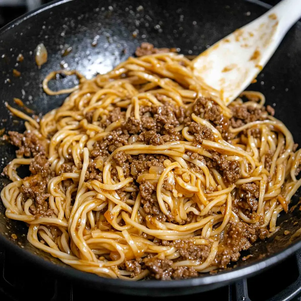 A wok of Mongolian ground beef and sauce mixture simmering before combining with noodles.
