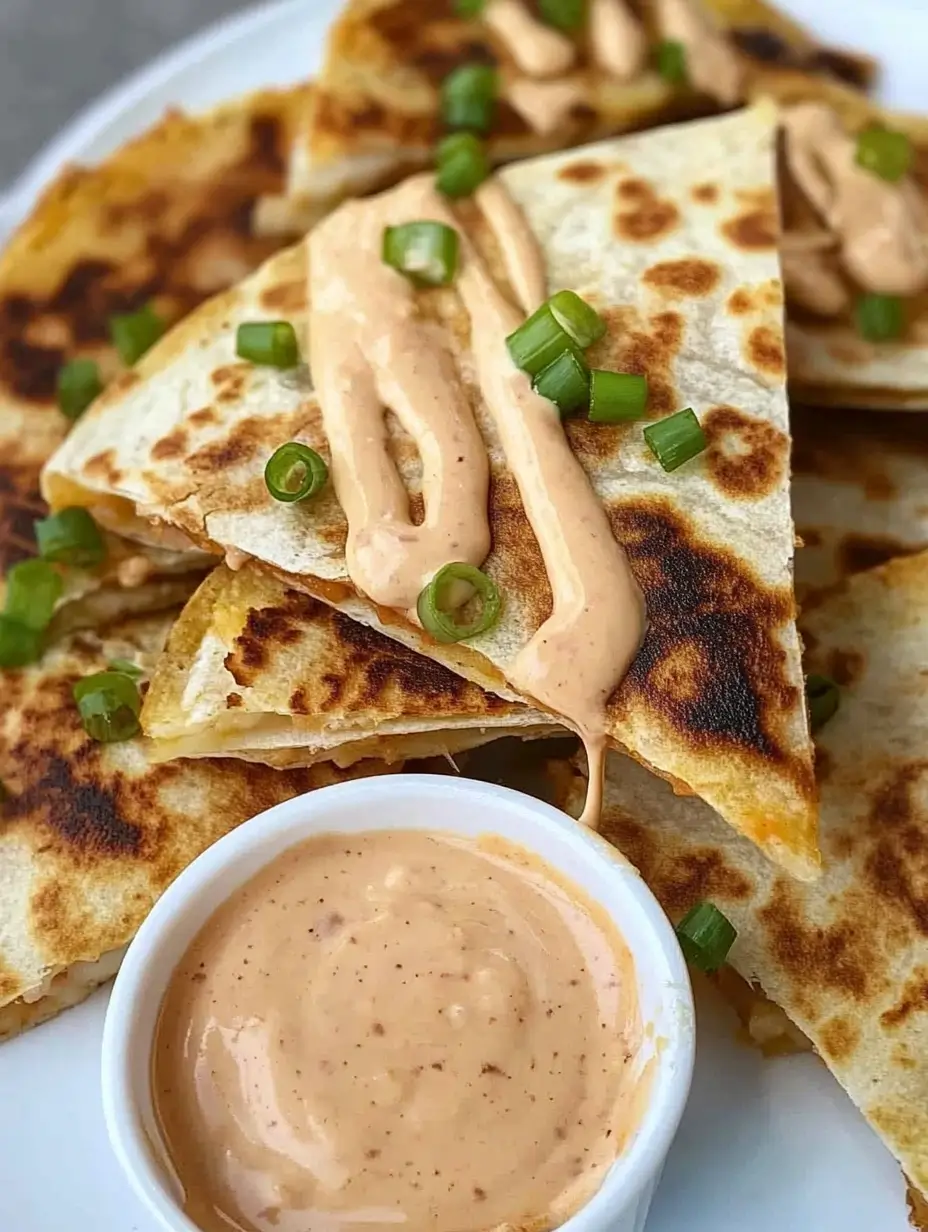 Steak Quesadilla Recipe You Can Whip Up Anytime 8 Steak quesadilla slices topped with creamy sauce and green onions, served with a dipping sauce.