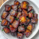 Air Fryer Pork Belly Bites 16 shiny-pork-belly-cubes-served-in-a-bowl-with-parsley-garnish