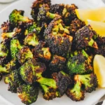 Frozen Broccoli in Air Fryer 18 perfectly-air-fried-broccoli-florets-on-a-white-plate-with-lemon-slices