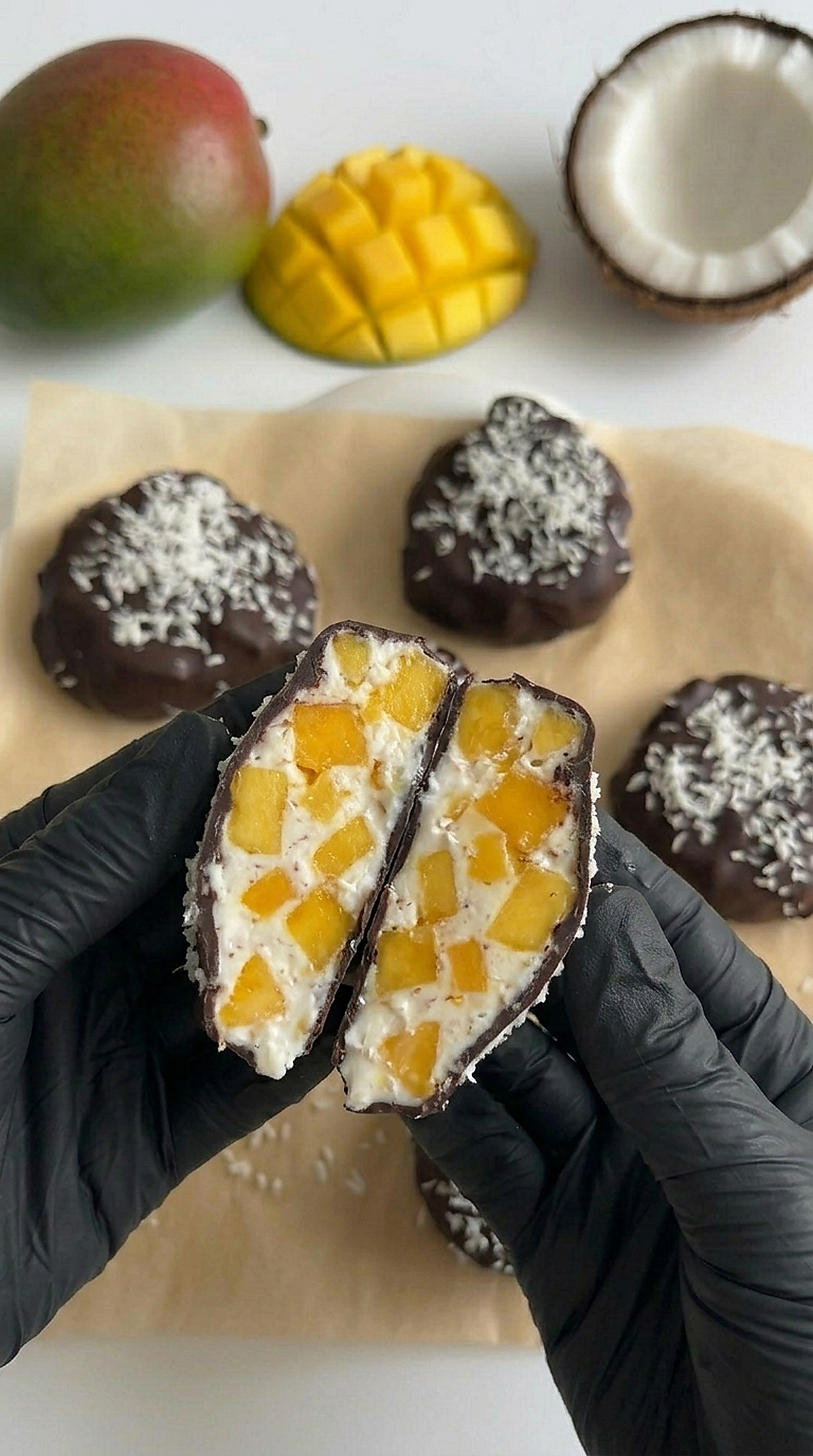 Chocolate Mango Yogurt Bites cut in half showing creamy mango yogurt filling inside dark chocolate shell with shredded coconut on top