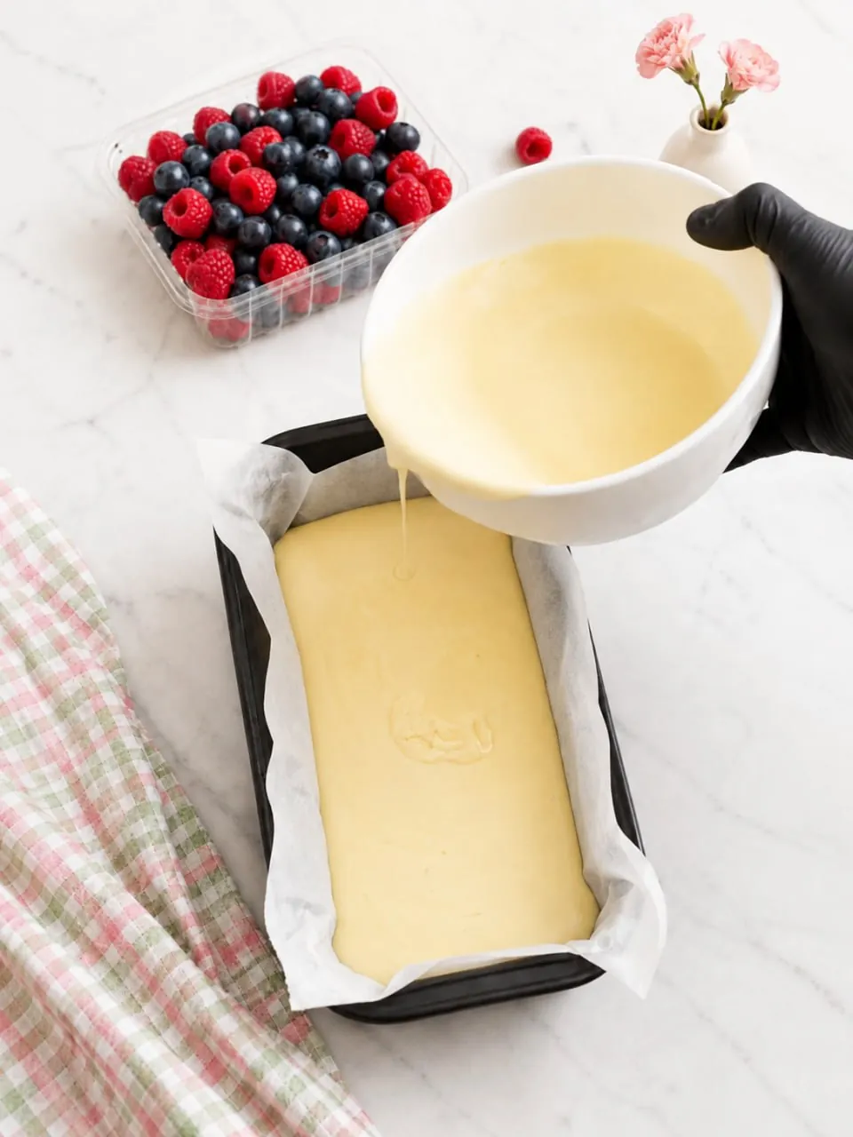 Pouring yogurt cake batter into a parchment-lined loaf pan